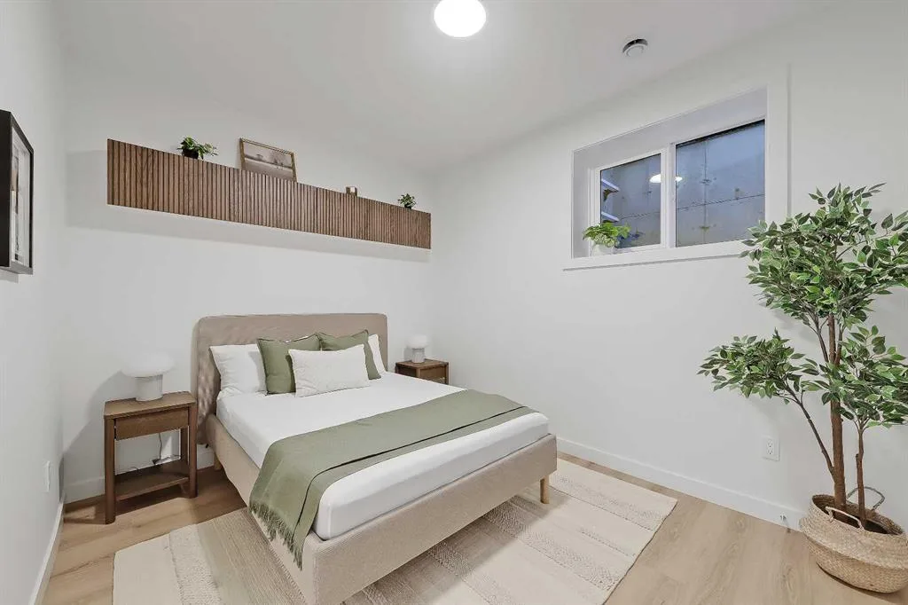 Second bedroom with upholstered bed and potted tree