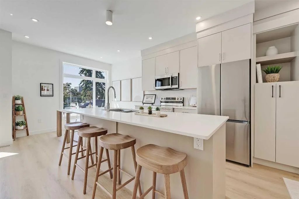 Kitchen island with wood bar stools, quartz waterfall countertop, and stainless steel appliances
